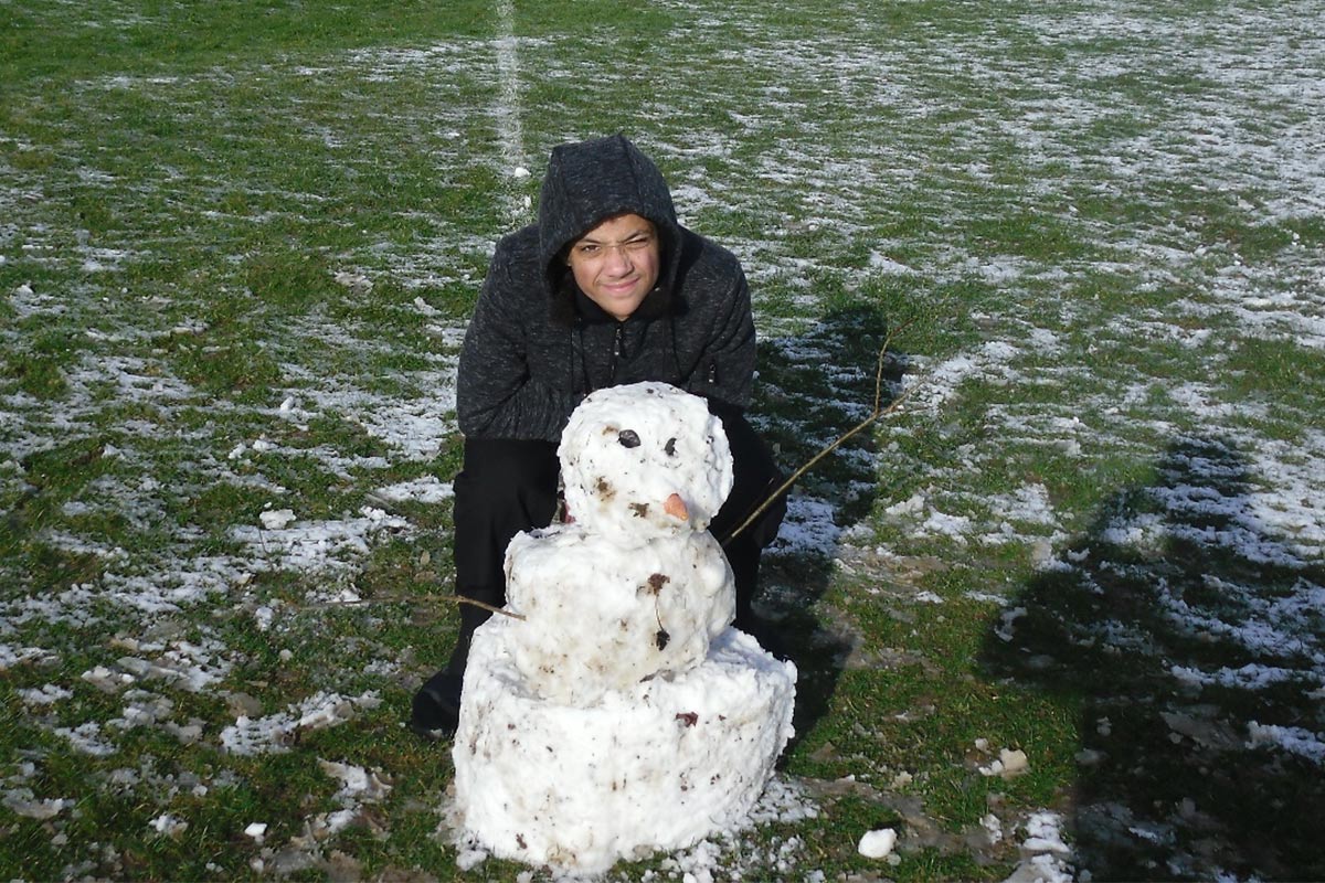 A student proudly showing off a snowman